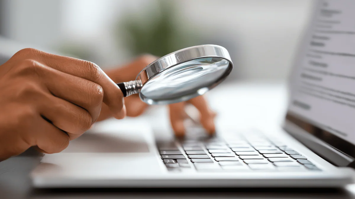 Website analysis using a magnifying glass over a laptop keyboard