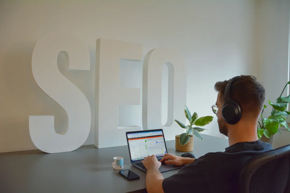 Profesional con auriculares redactando contenidos SEO en un portátil